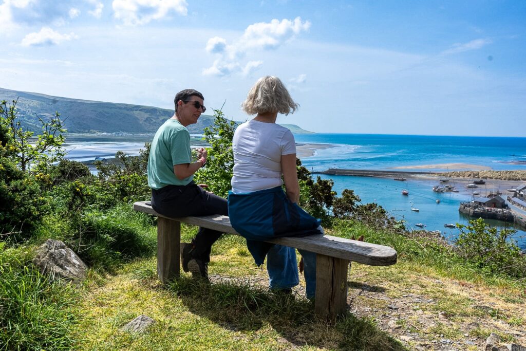 Nadine sitting with a client on a bench overlooking the sea